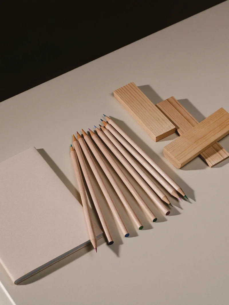 Farbstifte, Balsaholzleisten und ein schlichtes Skizzenbuch auf einem hellen Basteltisch